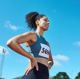 woman athlete, confident runner on stadium field and ready smile for brazil marathon competition. sports fitness motivation, strong happy girl training body for cardio race and healthy winning goal