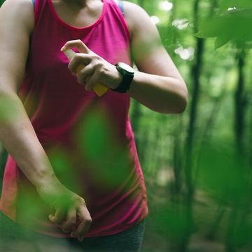 woman athlete using mosquito repellent in a forest