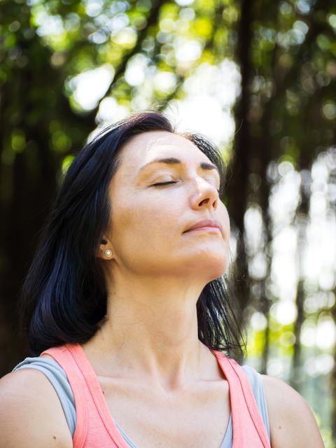 Closeup Caucasian adult woman face. Action breathing and relaxing in park. In yoga or meditation activities.