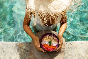 vrouw die smoothiebowl eet in het zwembad, zomer