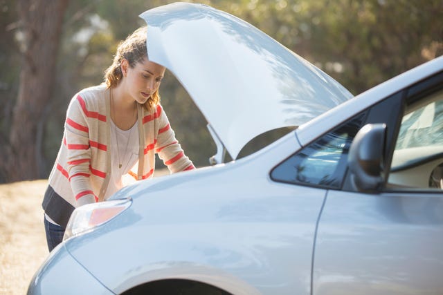 Woman checking car engine at roadside