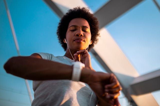 woman checking heart rate after sports training on bridge in morning time