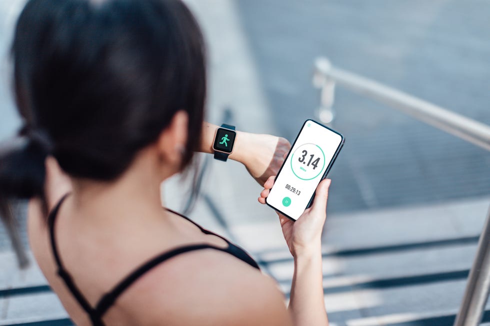 una chica mira en su smart watch y su móvil después de caminar