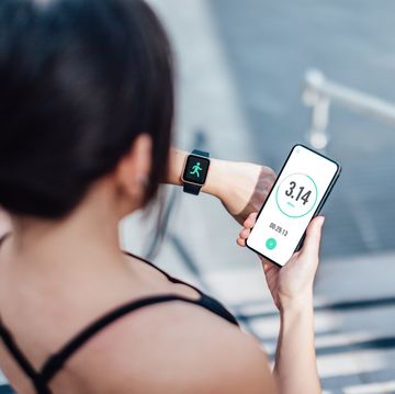 woman checking her smart watch and mobile phone after run