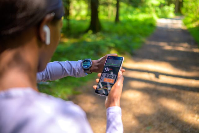 woman checking value in tracker software on smartphone and smartwatch