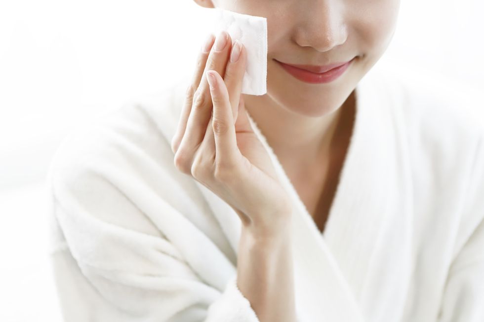 Woman cleaning face with cotton pad