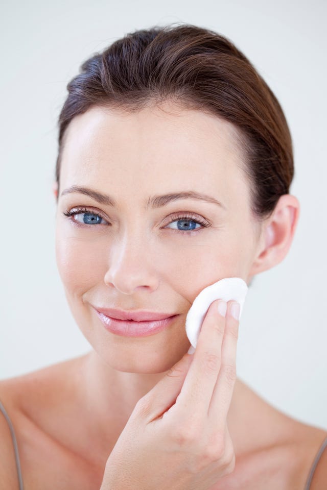 Woman cleaning face with cotton wool