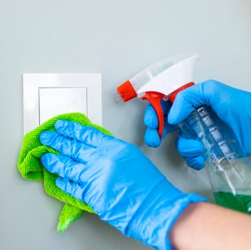 Woman cleaning a light switch with a disinfecting spray woman cleaning a light switch with a disinfecting spray