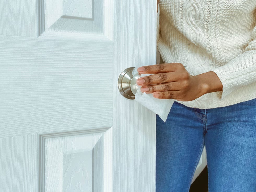 woman cleans interior doorknob using disinfectant wipe