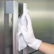 woman cleans refrigerator handle using disinfectant wipe, coronavirus concept, covid 19
