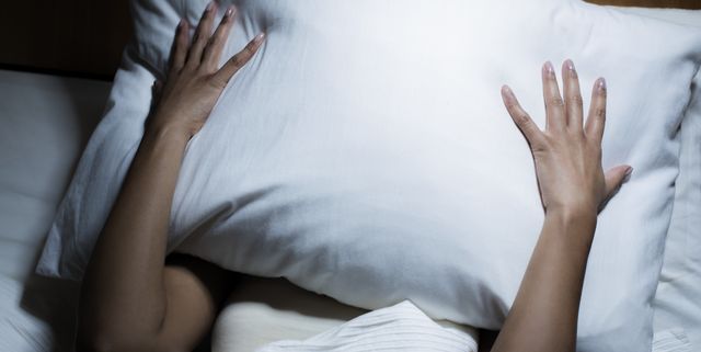 Woman covering her face with pillow