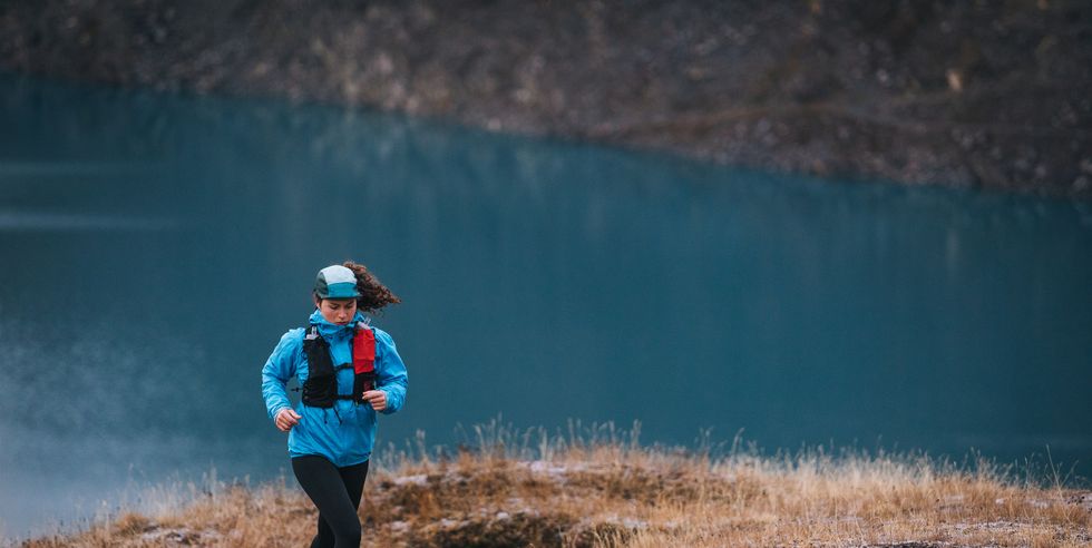 woman cross country runner ascends trail above lake