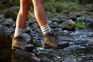 woman crossing stream wearing hiking boots