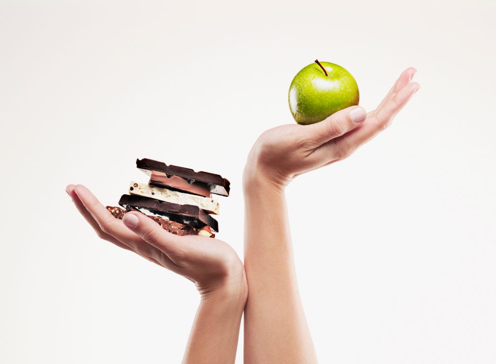 woman cupping green apple above chocolate bars