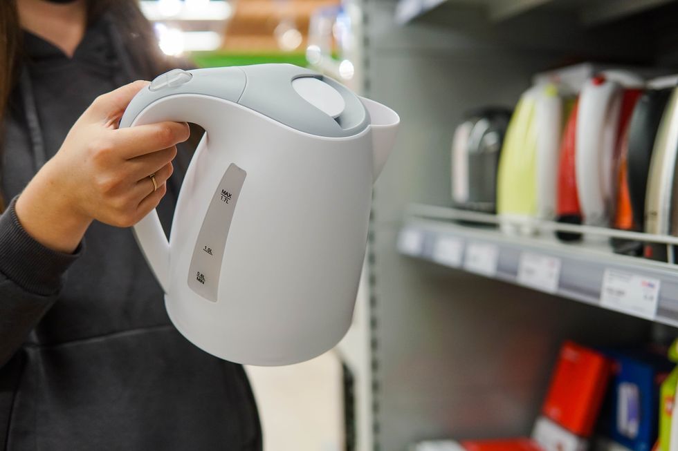 woman customer chooses an electric kettle at store, close up