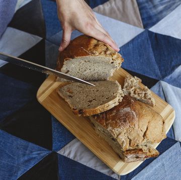 woman cutting bread loaf with knife at home