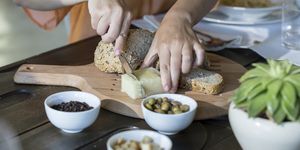 Woman cutting cheese and bread on chopping board