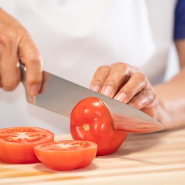 woman cutting fresh tomato: selective focus. diet and healthy food concept