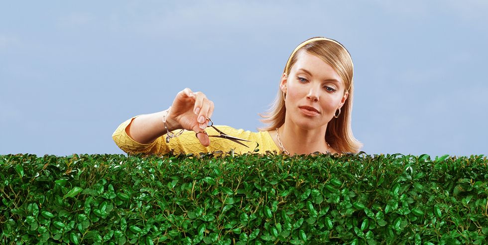 woman cutting hedge with scissors