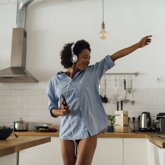woman dancing and listening music in the morning in her kitchen