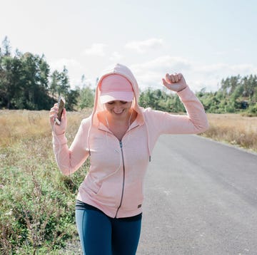 woman dancing outside listening to music on her phone with earphones