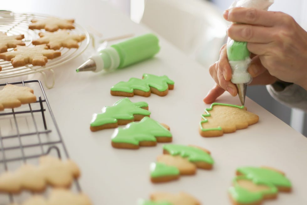 woman decorating cookies with green colored icing