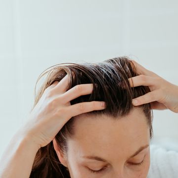woman delicately doing massage of her scalp with cosmetic oil