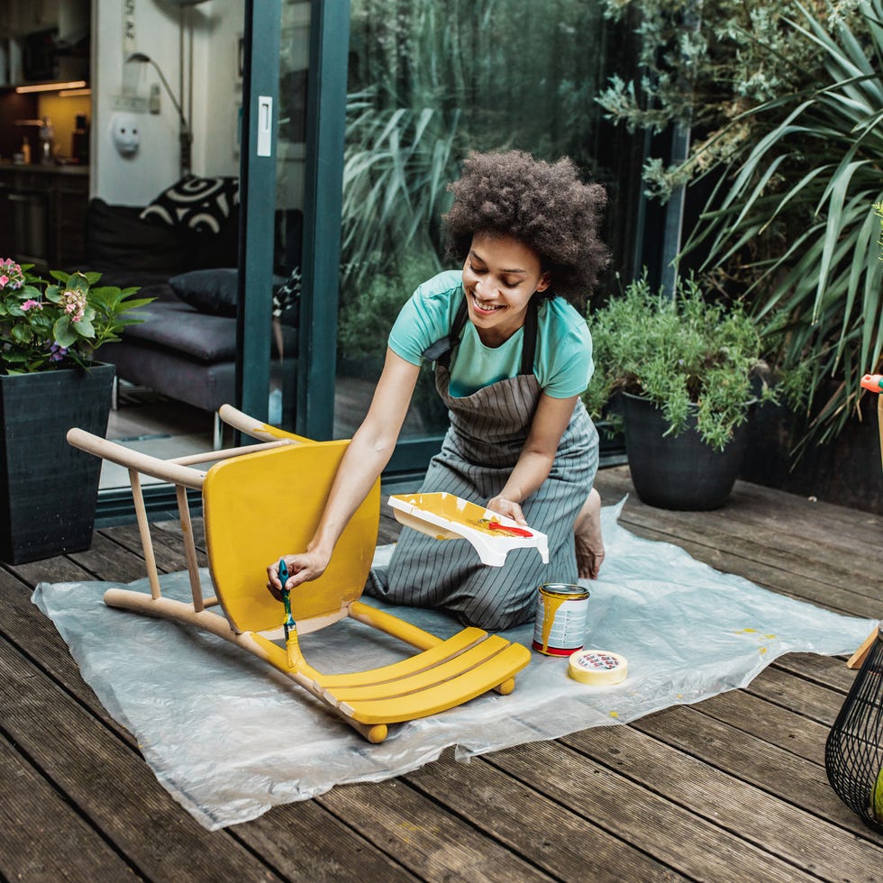 Self-care ideas woman painting a chair in the back yard