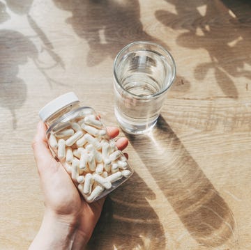 woman doctor nutritionist hands in white shirt with omega 3, vitamin d capsules with green vegan food the doctor prescribes a prescription for medicines and vitamins at the clinic