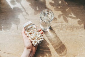 woman doctor nutritionist hands in white shirt with omega 3, vitamin d capsules with green vegan food the doctor prescribes a prescription for medicines and vitamins at the clinic