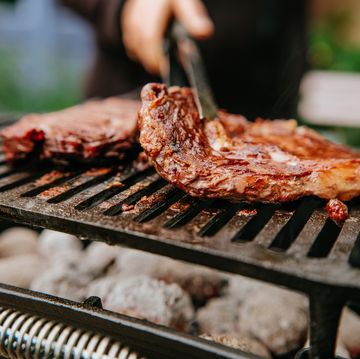 woman doing bbq steaks on a flame grill