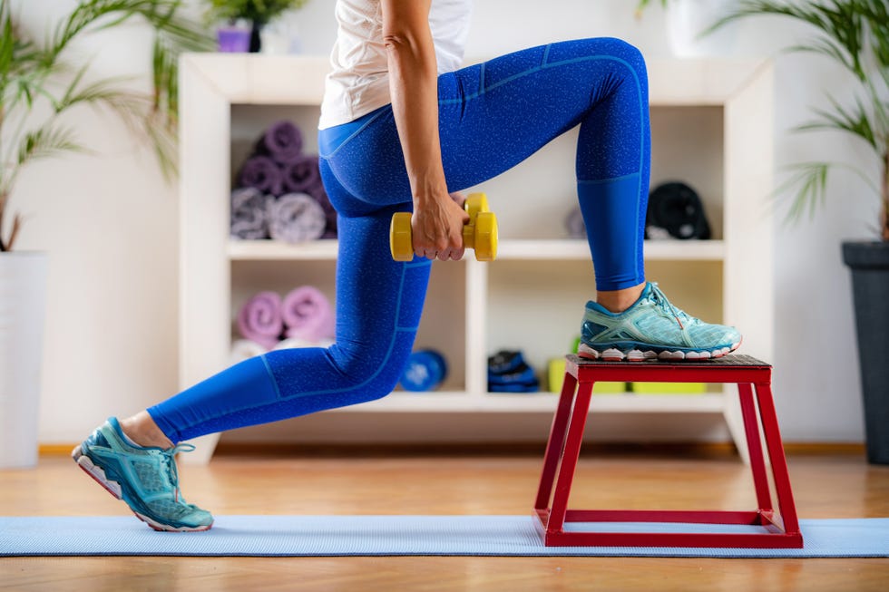 woman doing lunges with dumbbells on jumping stool