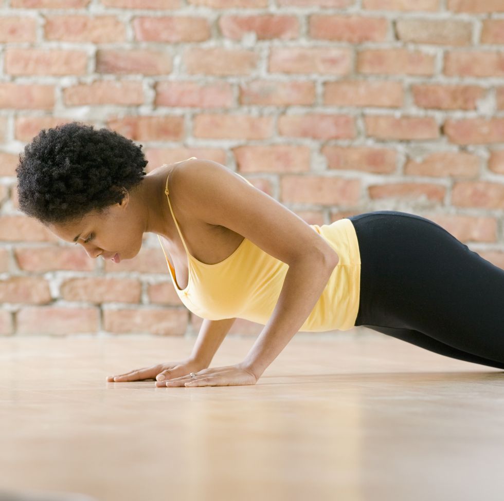 A Sporty Skinny Girl In A Black Workout Tight Suit Is Relaxing After Doing  Push-ups On The Blue Yoga Mat At Home. A Woman Is Practicing Exercises For  The Chest At Her