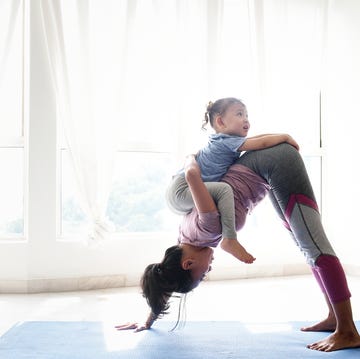 woman doing yoga with daughter on her back