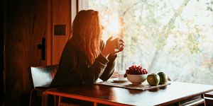 woman drinking coffee in a sunlit wooden cabin