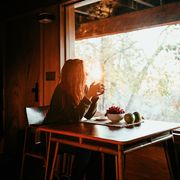 woman drinking coffee in a sunlit wooden cabin