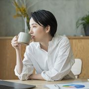 A woman drinking coffee while working remotely.