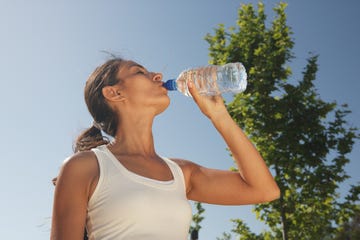 una chica bebe agua de una botella en un parque
