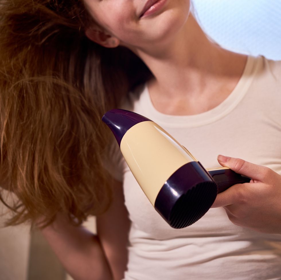 woman drying her hair with hairdryer