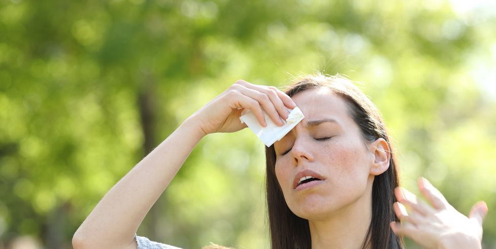woman drying sweat using a wipe in a warm summer day
