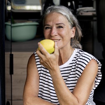 woman eating apple at doorway of camper van