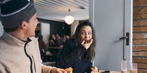 woman eating breakfast while sitting with friend at table in log cabin
