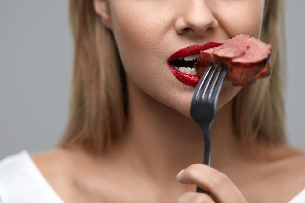 woman eating meat closeup of beautiful female face biting meat
