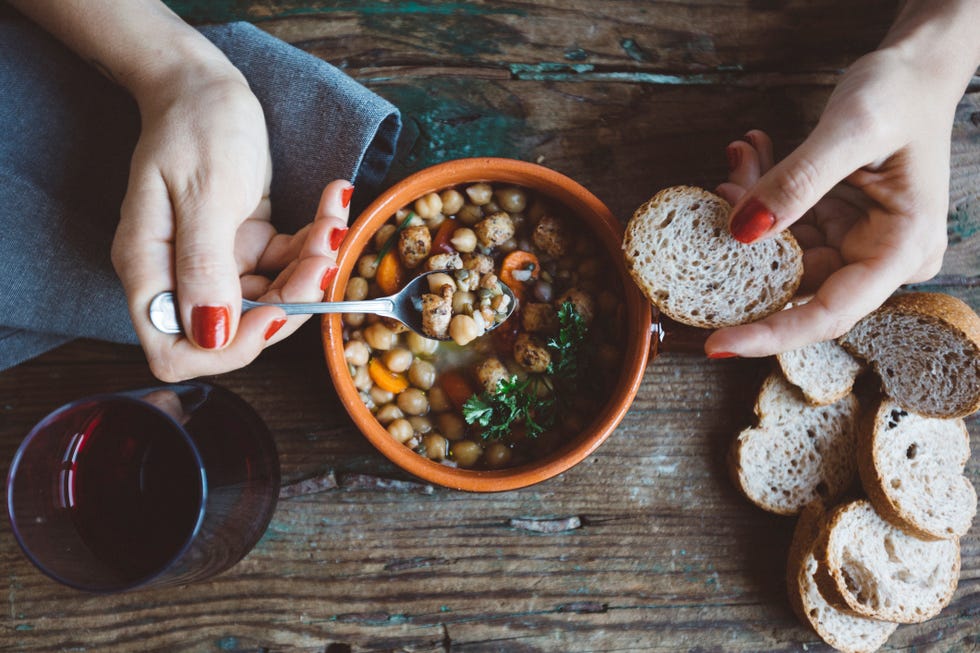 woman eating mediterranean soup with bread, close up