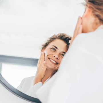 woman enjoys routine applying moisturizing cream on face