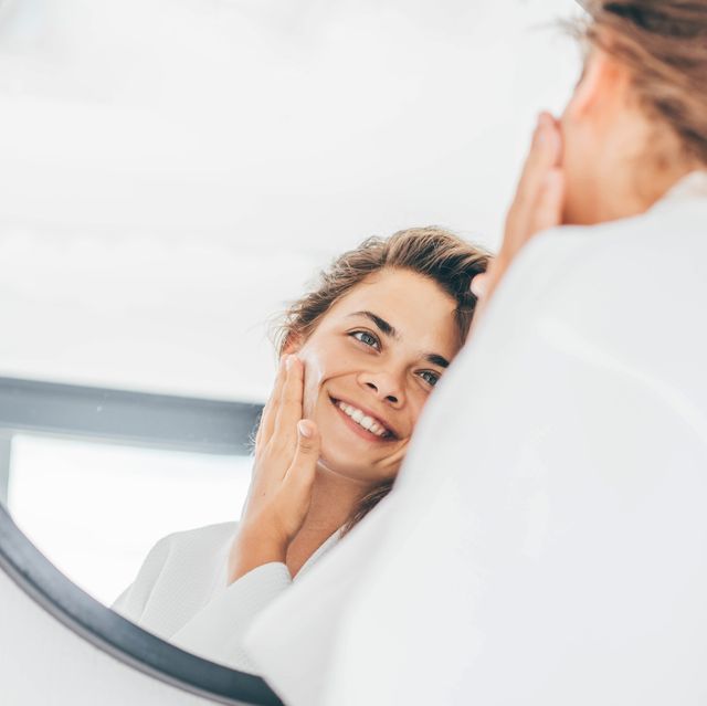 woman enjoys routine applying moisturizing cream on face
