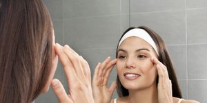 woman examining her face in mirror