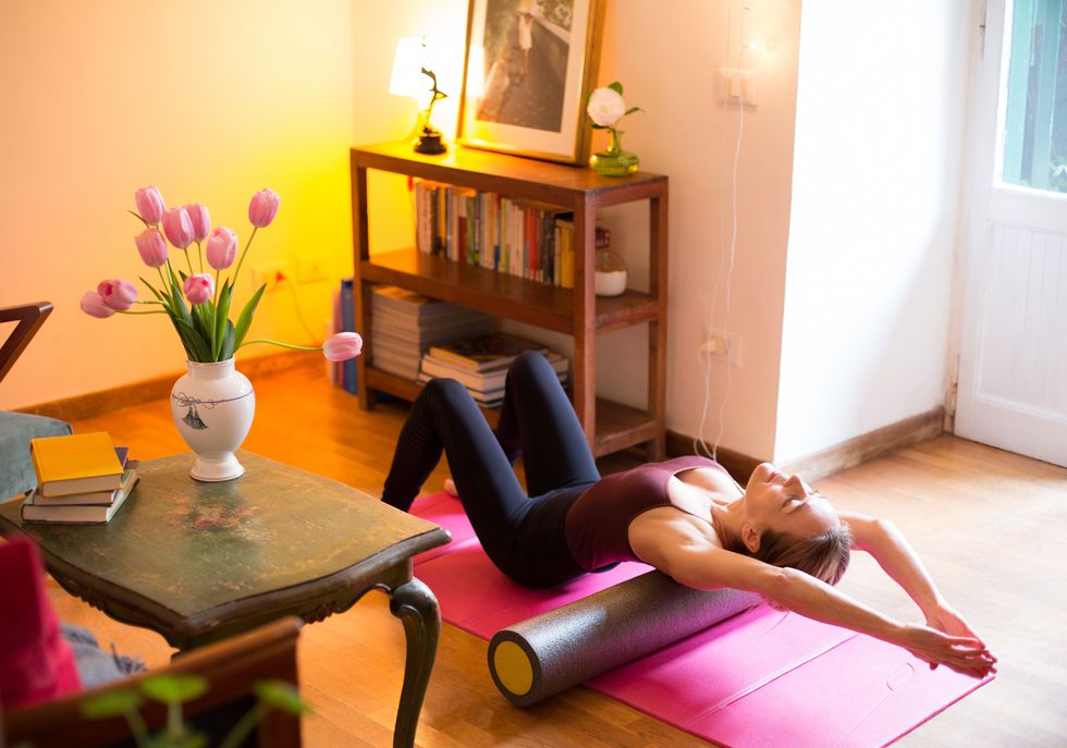 woman exercising at home, using foam roller