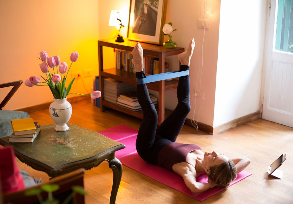 woman exercising at home, using resistance band