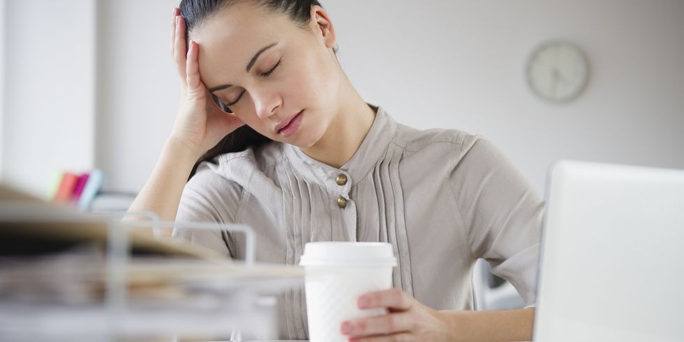 woman exhausted at desk with coffee